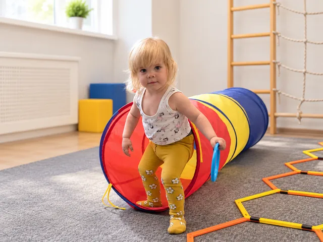 Девочка с синим кольцом выходит из цветного игрового тоннеля